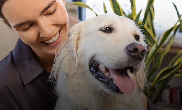 Frau lächelt, während sie einen Hund hält, der sichtbare den Pet Tag trägt