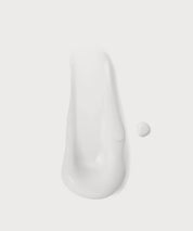 Weiße, cremige Textur des „Clean Skin“ Cleansers als Produkt-Swatch auf hellem Hintergrund, mit kleinem Tropfen daneben.