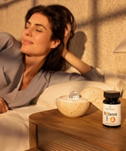 Eine Frau, die sich im Bett entspannt, neben ihr auf dem Nachttisch die Nahrungsergänzungsmittel Dormea und ProEnergetic Balance Caps.