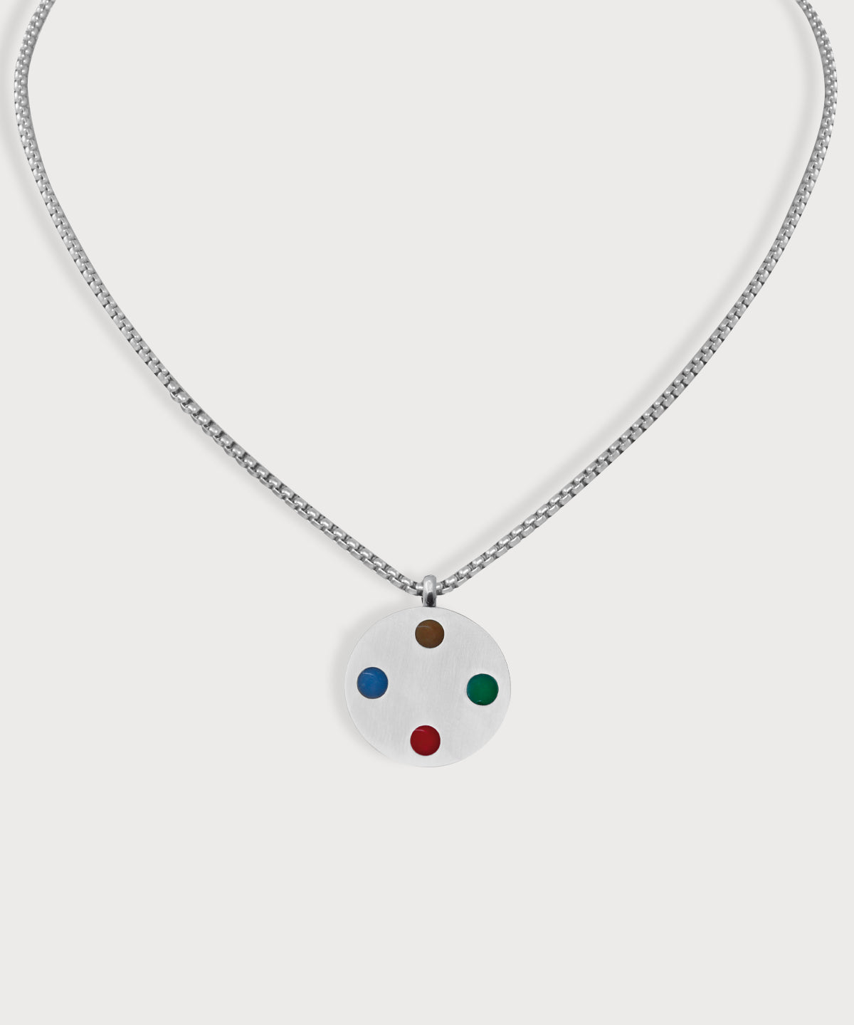 Silberfarbene E-Protect Necklace Halskette von ProEnergetic mit rundem Anhänger und vier farbigen Punkten auf hellem Hintergrund.