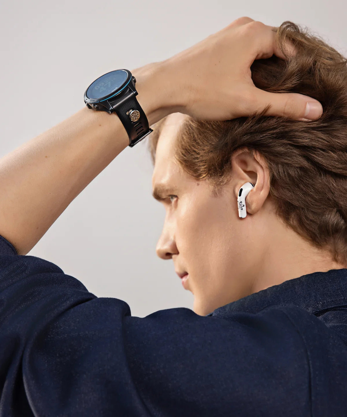 Mann im Innenraum mit seitlicher Ansicht trägt eine schwarze Smartwatch mit angebrachtem E-Protect Element am Handgelenk