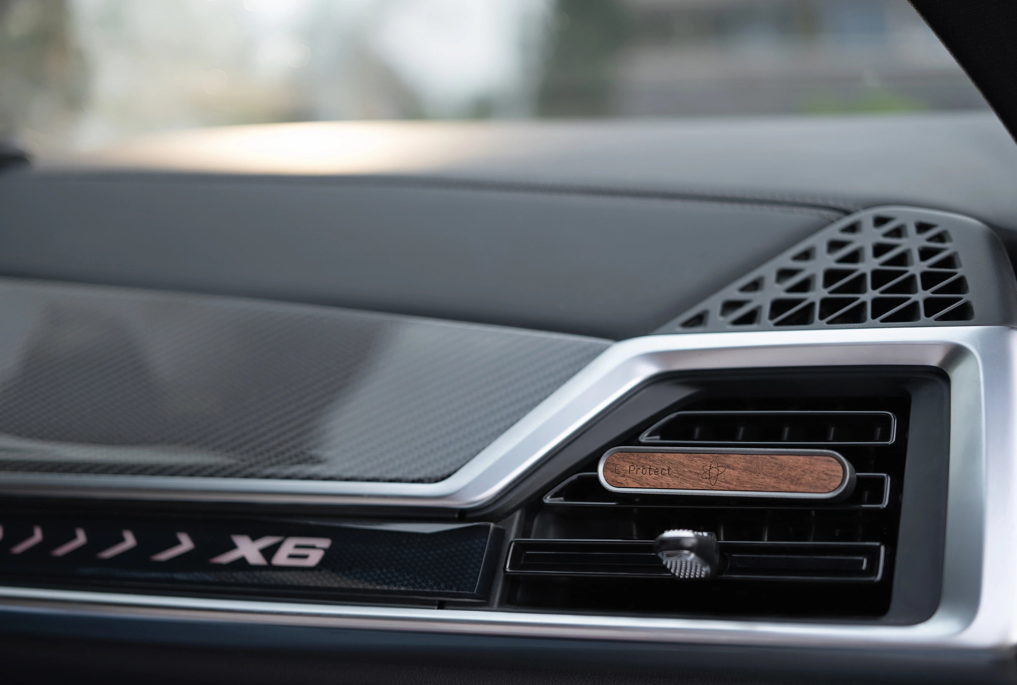 E-Protect Car Clip aus Holz ist an der Lüftungsdüse im Fahrzeuginnenraum befestigt, Armaturenbrett sichtbar