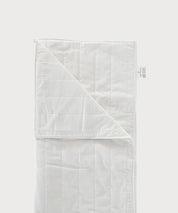 Weiße Grounding Sleep Mat mit gesteppter Oberfläche, teilweise aufgeklappt und mit sichtbarem Textiletikett auf hellem Hintergrund