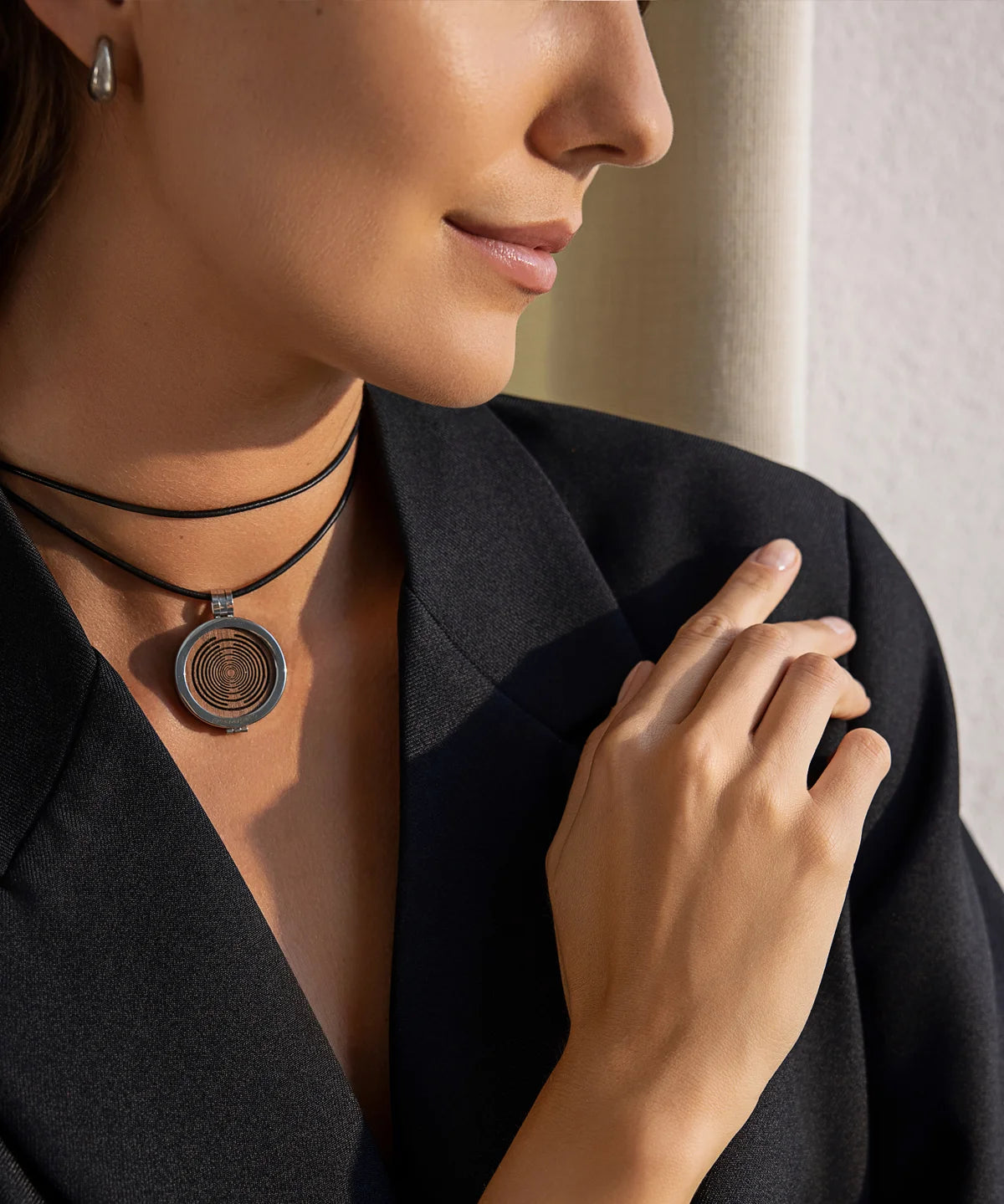 Detailaufnahme einer Frau im Innenraum mit getragener ProEnergetic KIER Protect Necklace am Hals, schwarzes Lederband und runder Anhänger sichtbar
