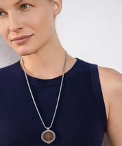 Frau trägt die ProEnergetic KIER Protect Necklace mit silberfarbener Kette und rundem Anhänger aus Metall mit sichtbarer Holzscheibe am Hals