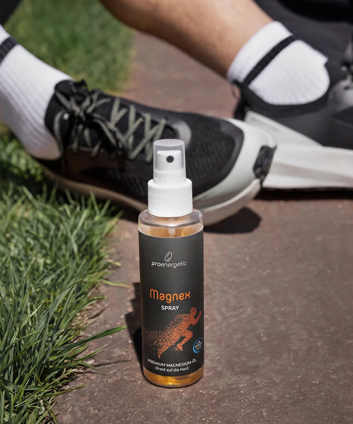 Das ProEnergetic Magnex Spray steht neben Laufschuhen auf einem Parkweg und verdeutlicht damit seine Verwendung vor oder nach dem Sport.