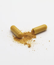 Eine geöffnete Motion Caps Kapsel mit gelblich braunem Pulver und eine geschlossene Kapsel auf hellem Hintergrund.