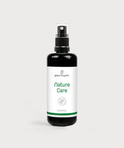 Dunkle Glasflasche mit Sprühkopf und Aufschrift Nature Care Essence auf hellem Hintergrund.