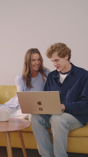 Mann sitzt im Innenraum auf einem Sofa, trägt eine schwarze Smartwatch mit angebrachtem E-Protect Element und legt sich anschließend hin, um zu telefonieren