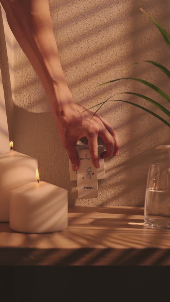 Hand steckt im Innenraum ein E-Protect S90 Steckelement in eine Wandsteckdose neben brennenden Kerzen