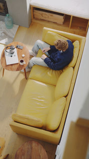 Mann legt sich im Innenraum auf ein Sofa, hält ein Smartphone am Ohr und telefoniert