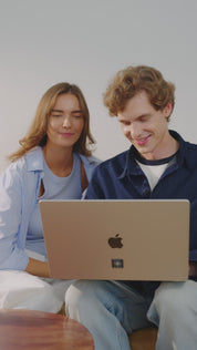 Mann sitzt im Innenraum auf einem Sofa, trägt eine schwarze Smartwatch mit angebrachtem E-Protect Element und legt sich anschließend hin, um zu telefonieren