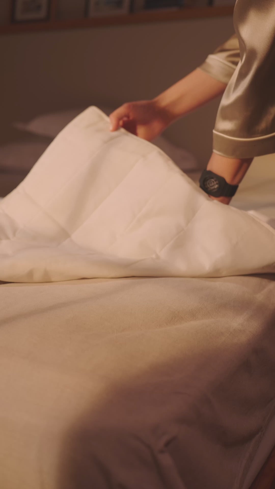 Person legt eine Grounding Sleep Mat unter das Laken auf das Bett und legt sich anschließend zum Schlafen hin