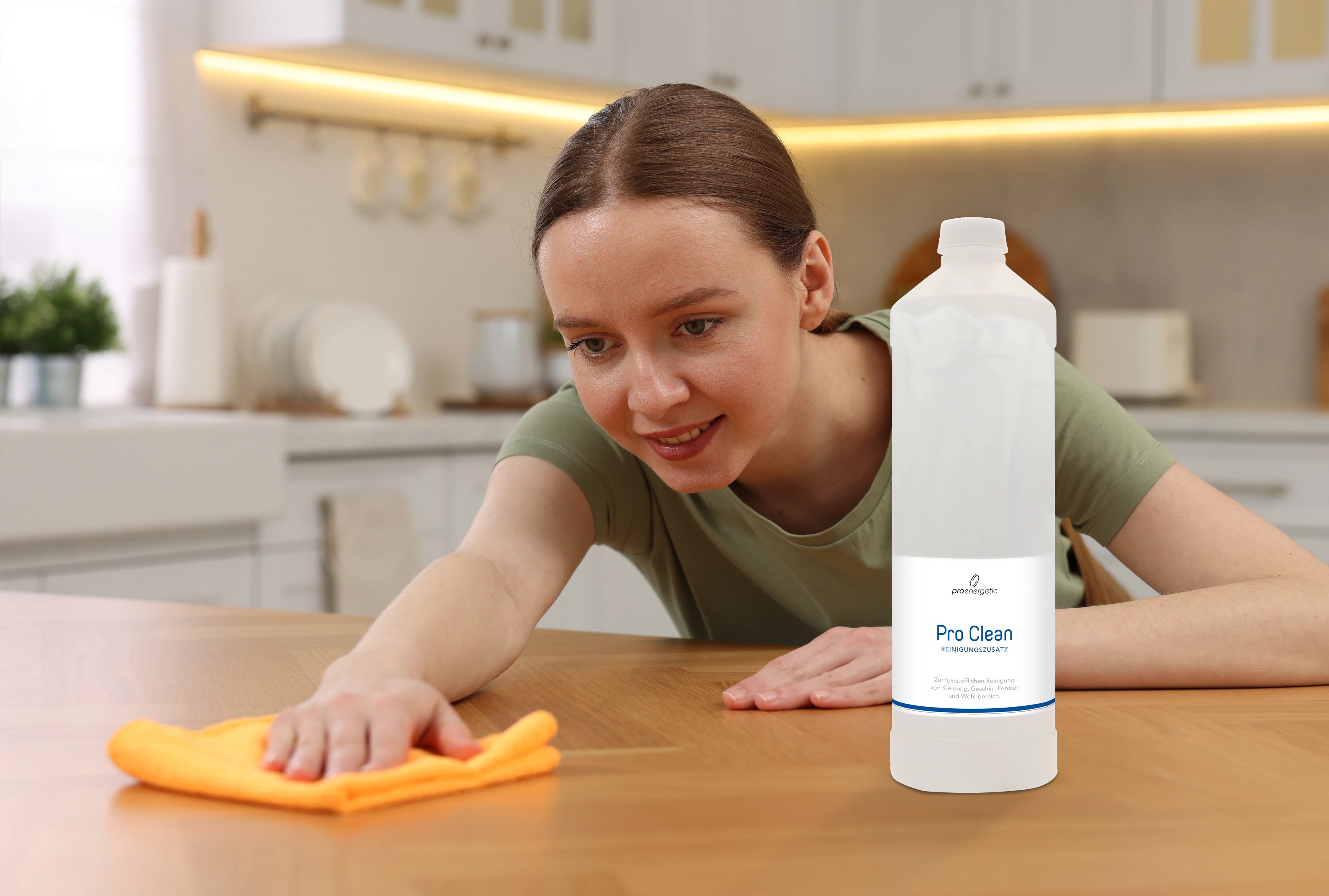 Person wischt eine Holzarbeitsfläche in der Küche mit einem Tuch, daneben steht die Pro Clean Flasche auf der Arbeitsfläche