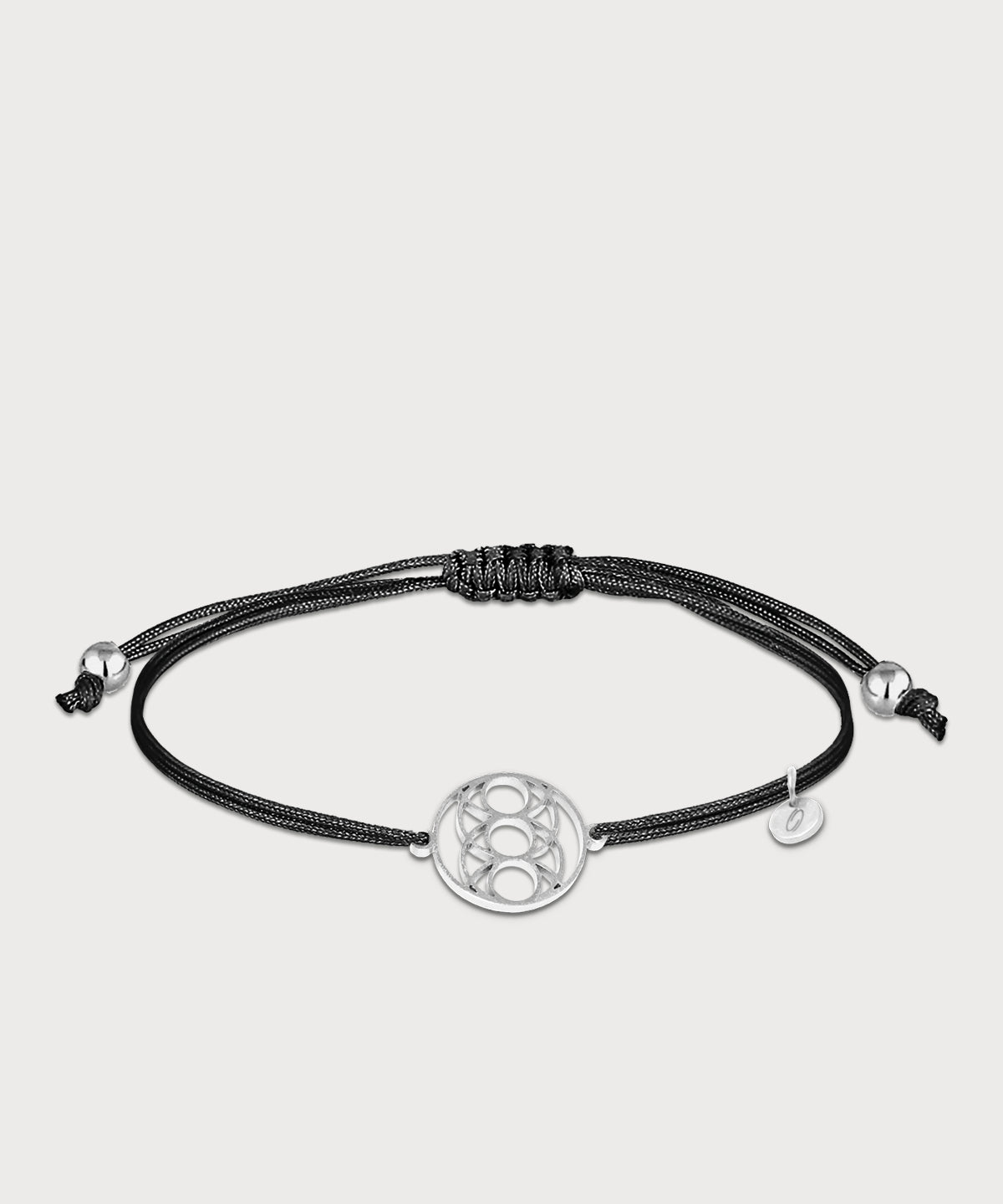 Schwarzes Seed of Happiness Armband mit silberfarbenem Symbol und verstellbarem Band auf hellem Hintergrund
