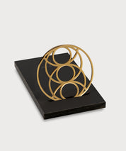 Seed of Happiness Goodie als goldenes Ornament mit kreisförmigem Design auf schwarzem Sockel vor hellem Hintergrund