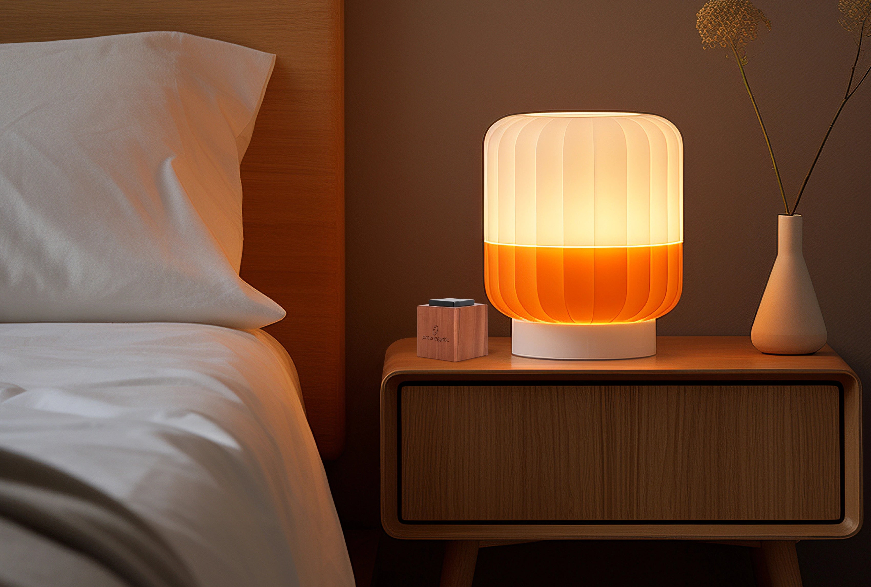 Nachttisch mit leuchtender Lampe und Sirius Holzwürfel von ProEnergetic neben dem Bett in einem Schlafzimmer.