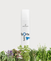 Weiße Pumptube „Sports Balm“ mit blauem Logo, vor grünen Kräutern und Pflanzen, freigestellt auf hellem Hintergrund.